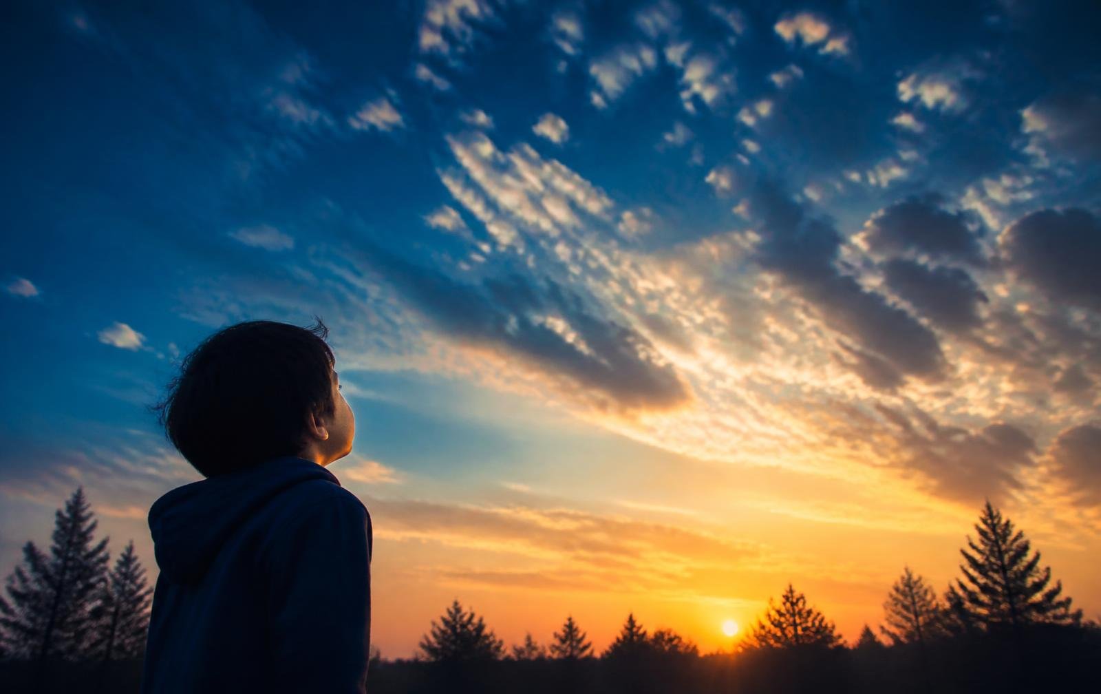 A child looking toward the sunrise sky